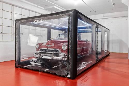 Classic car fully enclosed in a protective car capsule bubble inside the storage facility