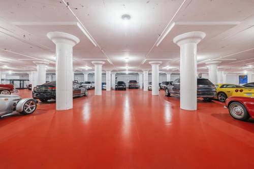 Multi-level indoor storage with rows of classic and modern cars on red polished floor